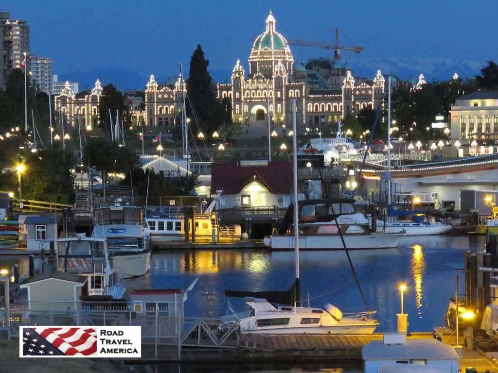Victoria harbour at night, with the Parliament Legislative Assembly building in the distance outlined in lights